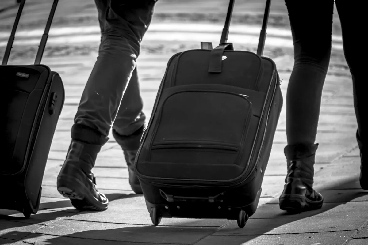 Two travelers pulling rolling suitcases in black and white